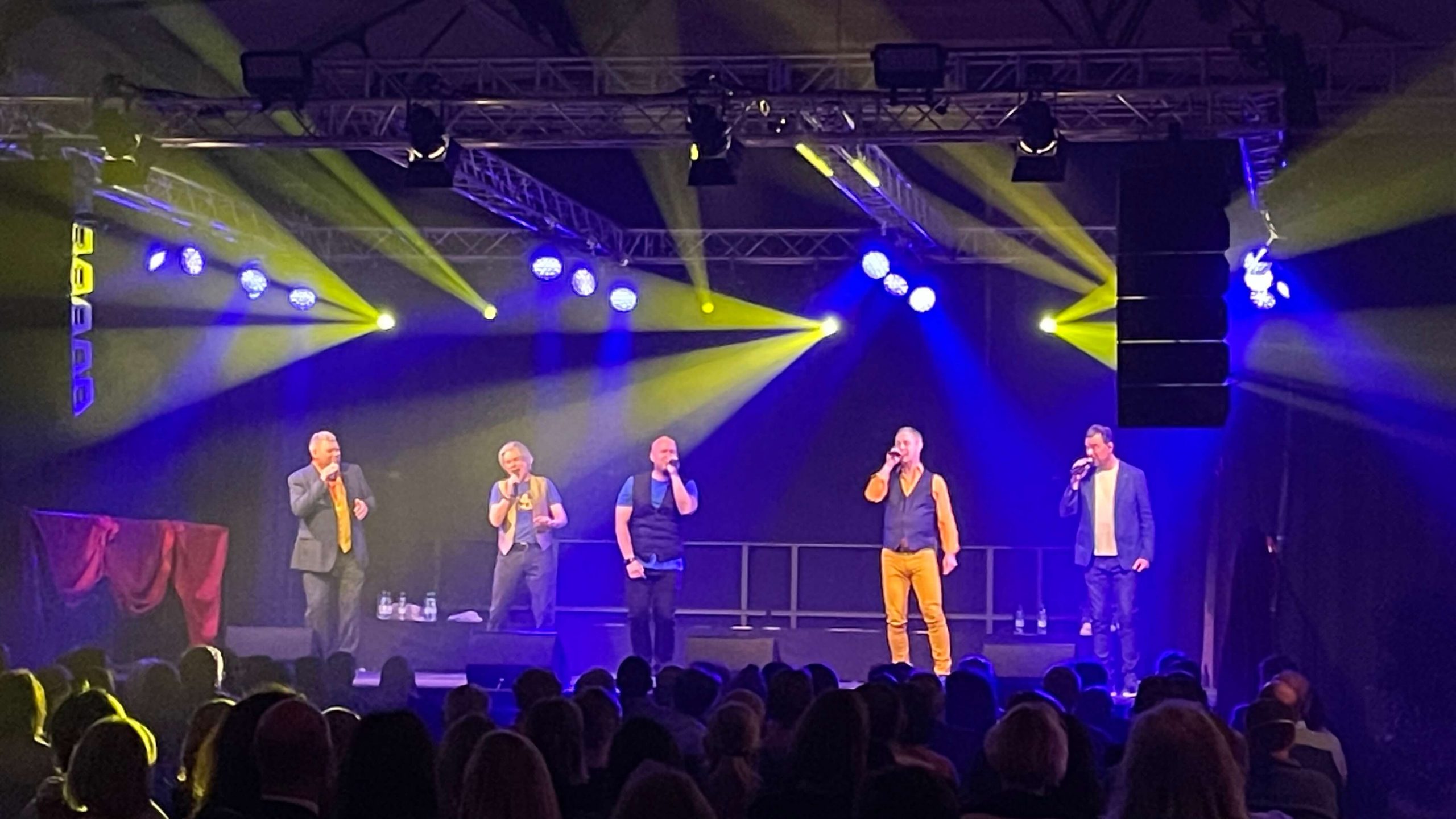 Lichttechnik auf einer Bühne mit fünf singenden Männern
