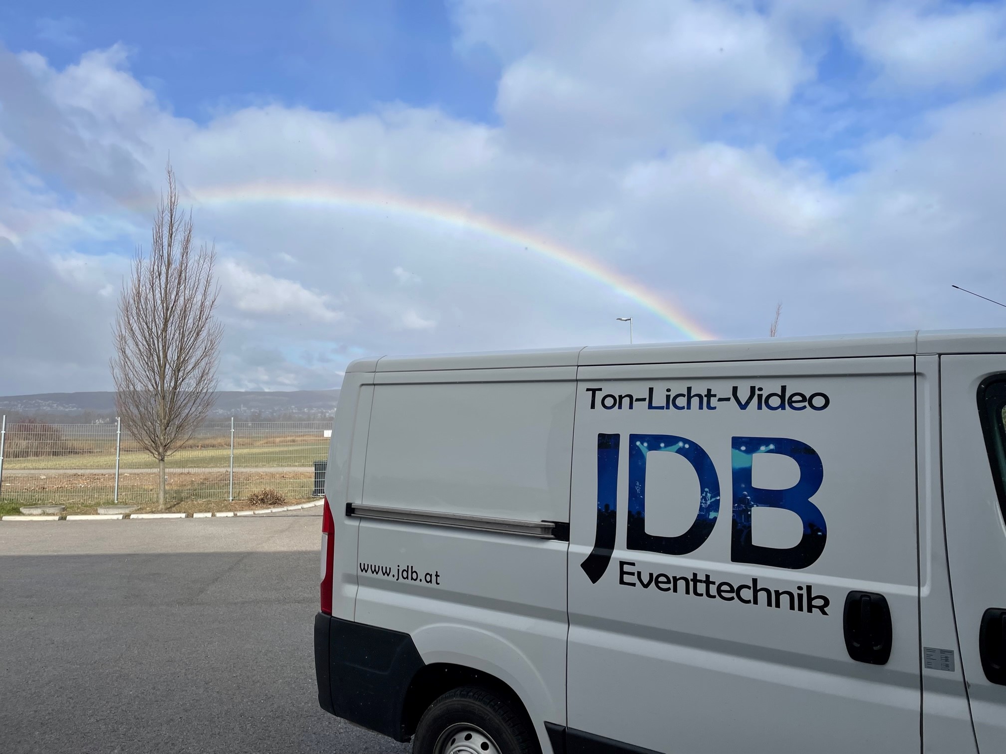 Fahrzeug mit "JDB" Beschriftung mit einem Regenbogen im Hintergrund