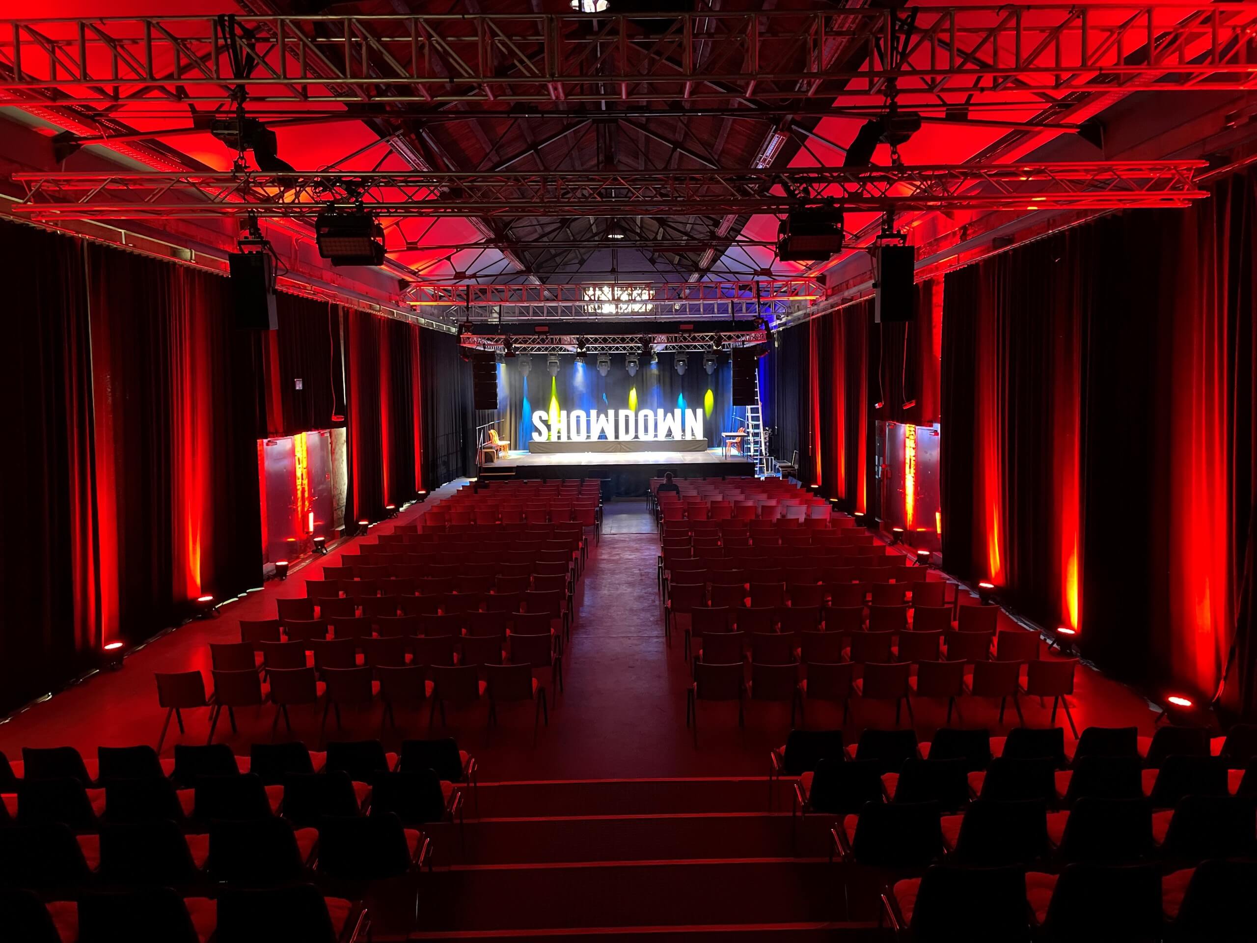 "Showdown" Bühnenbild mit roten Lichtelementen auf den Seitenwänden der Halle